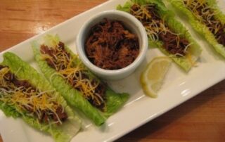 Four lettuce wraps with meat and cheese on a plate.
