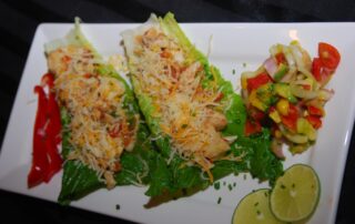 Two lettuce wraps with cheese and vegetables on a plate.