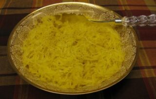 A bowl of yellow spaghetti with a spoon.