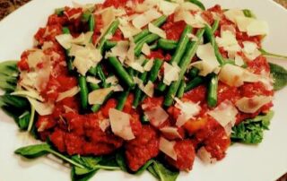 A plate with meat, green beans and parmesan cheese.
