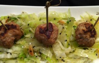 A plate with meatballs and cabbage on it.