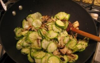 Zucchini and mushrooms in a frying pan.
